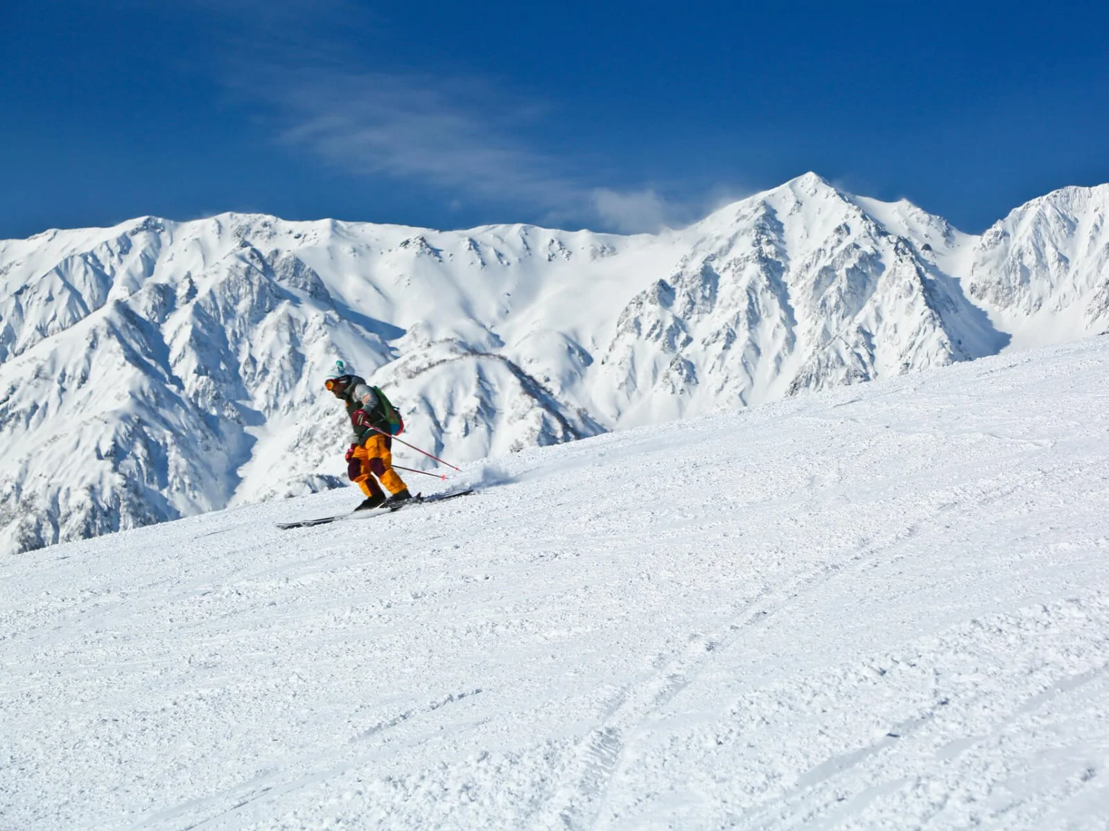Esquiador numa pista larga e preparada sob os picos nevados de Hakuba