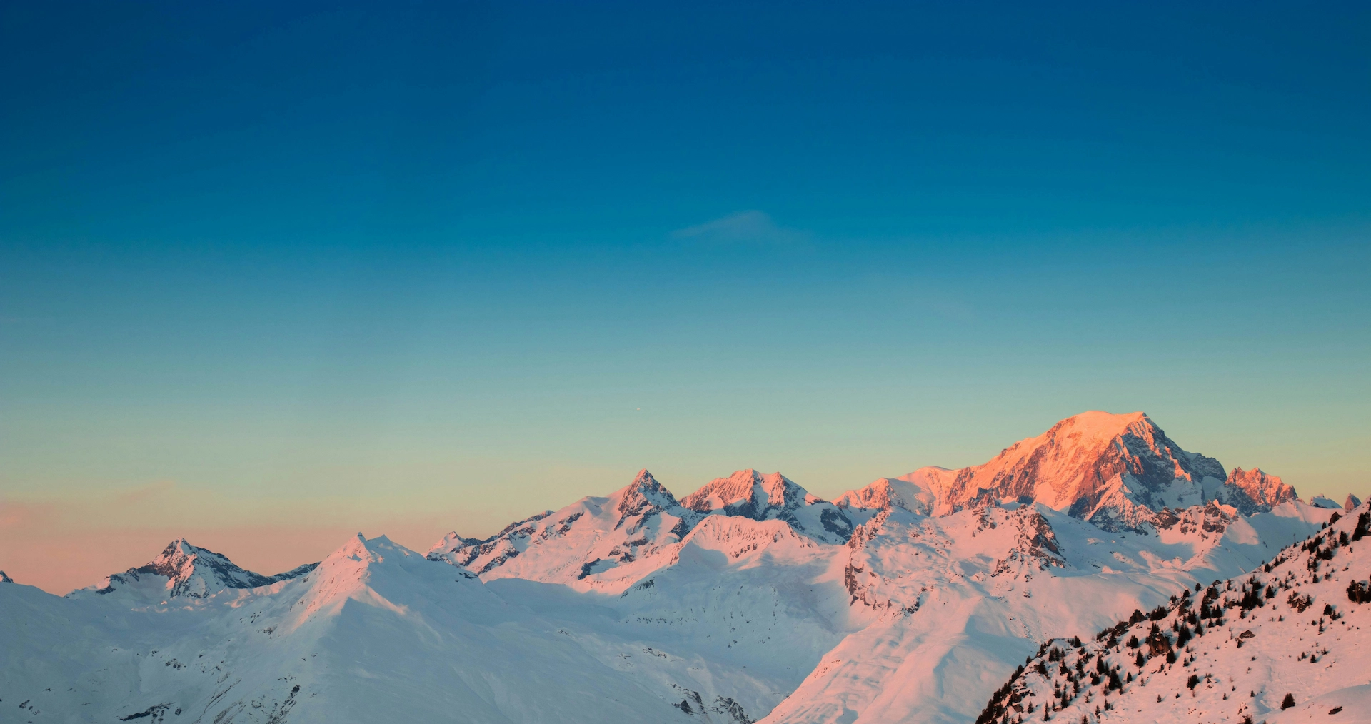 Snowy mountain peaks glowing pink at sunset